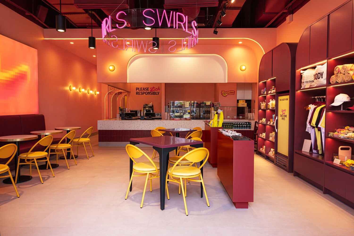Inside the Banana Daddy Midtown Miami shop with yellow chairs and the pink SWIRLS neon sign